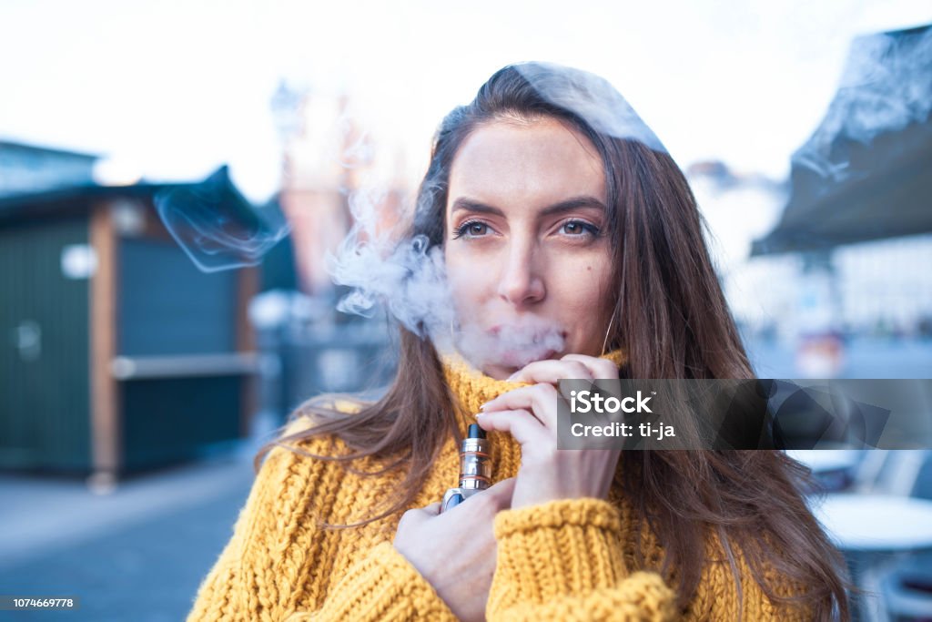 Woman vaping an electronic cigarette Caucasian woman vaping electronic cigarette outdoors. Electronic Cigarette Stock Photo