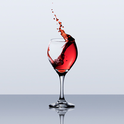 Pouring red wine into wine glass on a black background, studio shot
