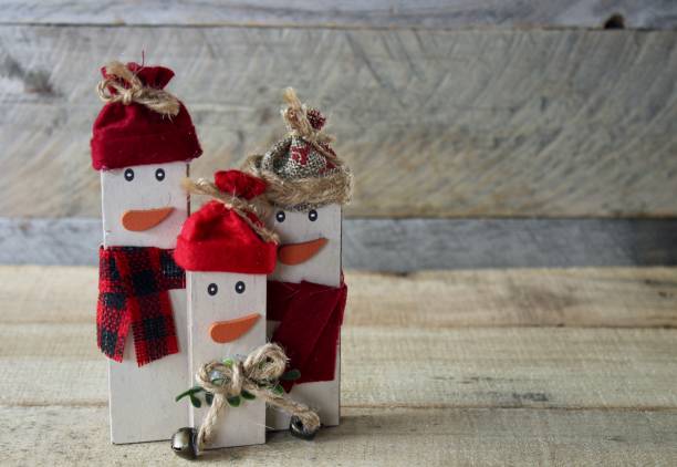 istock three rustic decorated wooden snowmen standing on wood with wood background 1074680140