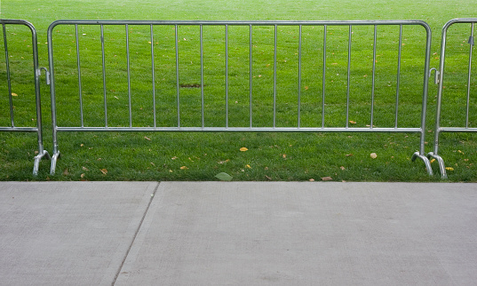 temporary pedestrian barrier set up for outdoor event to separate sidewalk and grass area