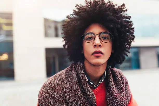 Close-up portrait of a young handsome curly guy. The headshoot of an Egyptian student. Serious facial expression Eyeglasses