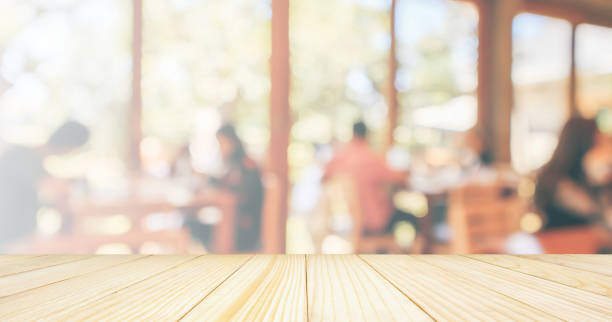 istock Empty Wood table top with Restaurant cafe or coffee shop interior with customer blur abstract vintage style bokeh light for montage product display background 1074689136
