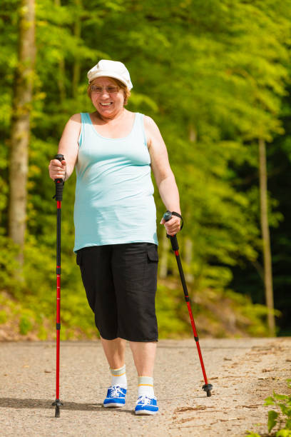 istock Senior woman practicing nordic walking in park 1074710356