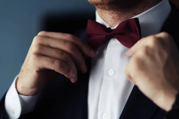 Photo of Grooms suit close up detail, groom wearing black suit in the wedding day with a flower attached