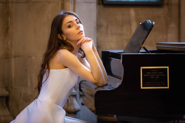 istock Beautiful Caucasian lady sitting at piano white dress 1074725708