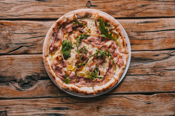 Overhead pizza carbonara on rustic wooden table