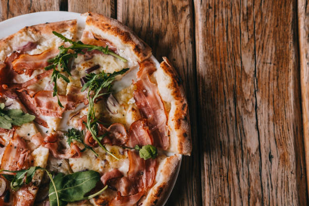 Overhead pizza carbonara on rustic wooden table Pizza carbonara on rustic wooden table. Food photography concept. Top view, copyspace cooked bacon slice stock pictures, royalty-free photos & images