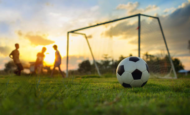 夕日の下での農村地域における運動のためサッカーを遊んでいる子供のグループのシルエット アクション スポーツ写真。 - soccer field dirty soccer outdoors ストックフォトと画像
