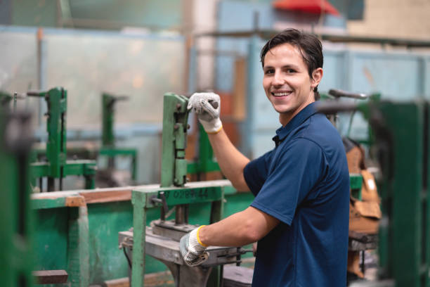 istock Cheerful latin american young worker at a shoe factory holding a machine while facing camera smiling 1074772496