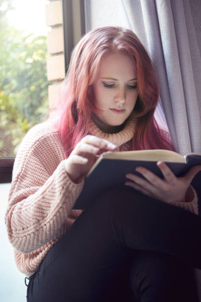 istock Young girl reading by a window 1074784910