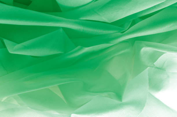 istock Texture, background, pattern. The texture of the silk fabric is green. Silk fabric is transparent. Fabric or liquid wave illustration of wavy creases of silk satin texture or velvet material 1074787272