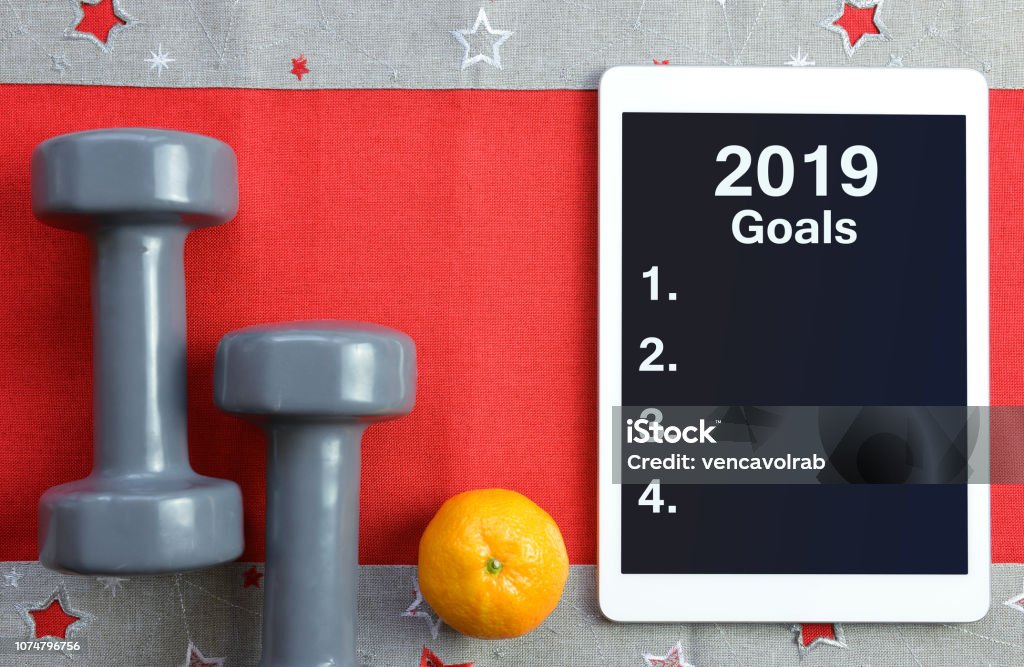 Healthy resolutions for the New Year 2019. Dumbbells with mandarin and tablet computer. Healthy resolutions for the New Year 2019. New Year Resolution Stock Photo