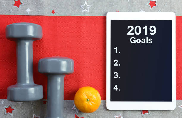 Healthy resolutions for the New Year 2019. Dumbbells with mandarin and tablet computer. Healthy resolutions for the New Year 2019. 2019 new year resolution stock pictures, royalty-free photos & images