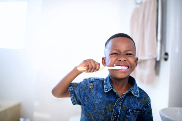 afrykański 6-7-letni chłopiec szczotkowanie zębów uśmiechając się - african descent child brown eyes ethnicity zdjęcia i obrazy z banku zdjęć