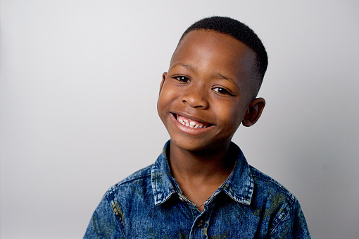 Cute African boy smiling head and shoulders Formal portrait with studio lighting Strand Cape Town South Africa