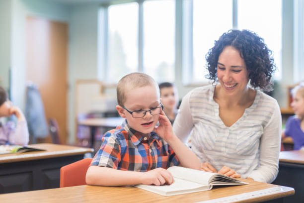 istock Young ethnic teacher helps a boy with an assignment at his desk 1074797374