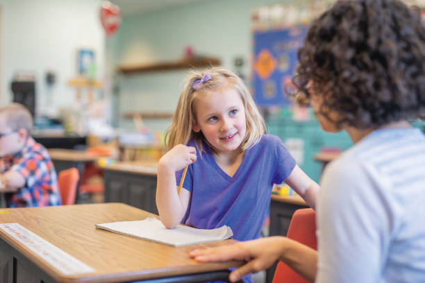 istock First grade girl talking with her teacher in the classroom 1074797388