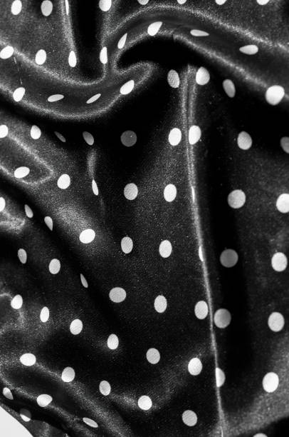 istock Texture, background, pattern. Girl's skirt. Silk fabric on a black background white polka dots 1074800366