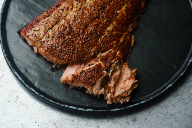 istock Smoked salmon with pepper on black stone plate on metallic surface 1074808038