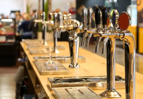 Photo of beer taps lined up on the counter of a pub