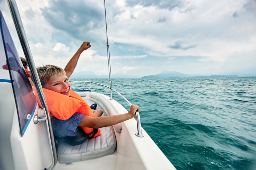 Family enjoying Garda Lake vacations. Father and kids riding a boat on Lake Garda.\nNikon D850