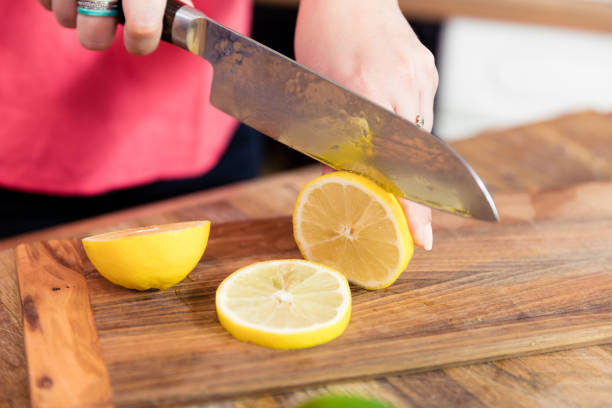 istock Close up of woman slicing lemon on cutting board. 1074811708