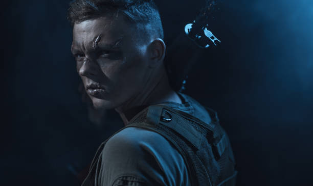 istock Serious Young Man With Facial Scars is Holding Automatic Rifle on Shoulder 1074812224
