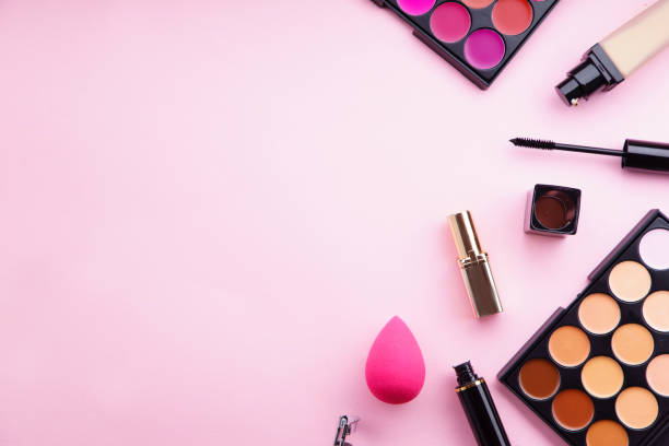 化粧品の上から見た画像: 口紅とコンシーラー パレット、ピンクの背景の財団、マスカラー、まつげカーラー。フェミニンなアクセサリー コンセプト - lash curler ストックフォトと画像