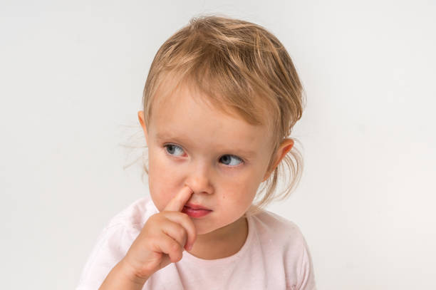 istock Baby girl is picking her nose with finger inside 1074826134