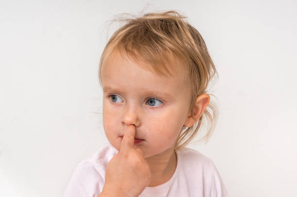 istock Baby girl is picking her nose with finger inside 1074826744