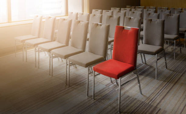 istock One red chair different from others in empty conference room 1074829566
