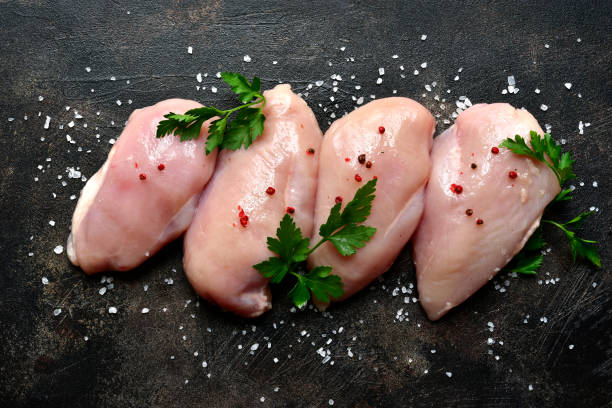 Raw organic chicken breast Raw organic chicken breast on a dark slate, stone, concrete or metal background.Top view with copy space. chicken breast photos stock pictures, royalty-free photos & images
