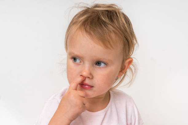 istock Baby girl is picking her nose with finger inside 1074831122