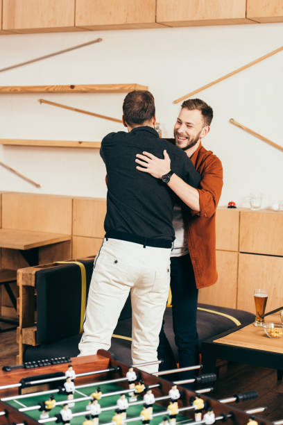 istock cheerful men hugging while greeting each other in cafe 1074835868