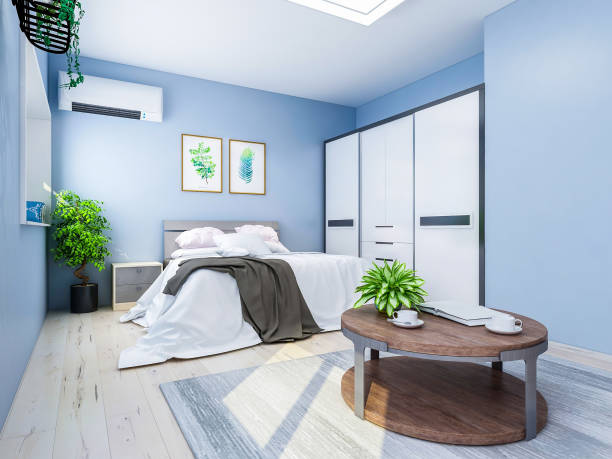 istock Spacious and unmanned bedroom design with solid wood custom closet and double bed in the blue walls, coffee table and decorations in front of the bed, TV, etc., green plants in the room 1074837428