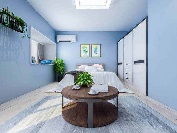 istock Spacious and unmanned bedroom design with solid wood custom closet and double bed in the blue walls, coffee table and decorations in front of the bed, TV, etc., green plants in the room 1074837432