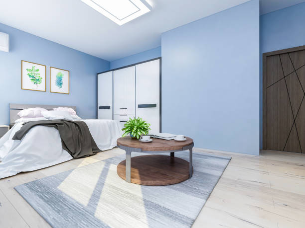 istock Spacious and unmanned bedroom design with solid wood custom closet and double bed in the blue walls, coffee table and decorations in front of the bed, TV, etc., green plants in the room 1074837440