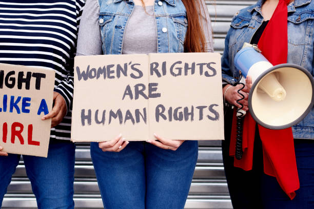 The time is now, the time is ours Cropped shot of an unrecognizable woman holding up a poster that reads "Women's rights are human rights" while protesting with other unrecognizable women in the city womens rights stock pictures, royalty-free photos & images