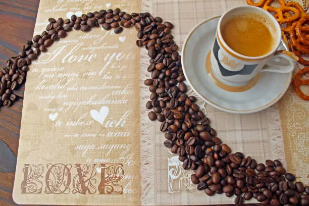 A cup of coffee with a saucer, cookies and coffee grains.