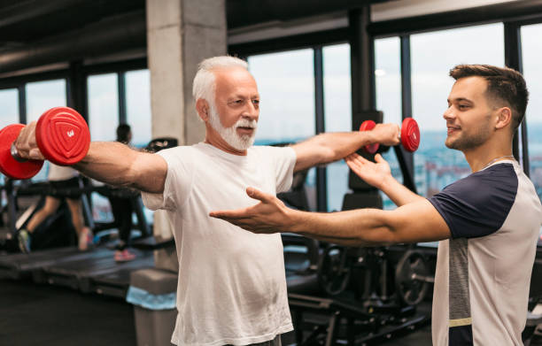 istock Senior man with dumb bells working out with fitness instructor 1074848862