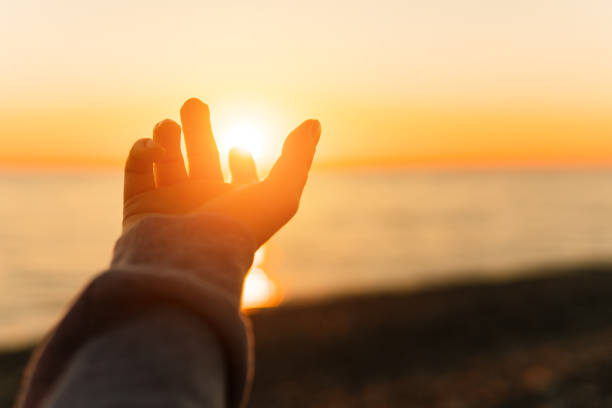 istock Hand reaching for sun. Sunset sun over the sea. 1074851950