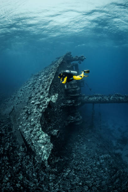 istock Scuba diver exploring a shipwreck that is completely consumed by sea life lying at it's side on the bottom of the Red Sea 1074851980