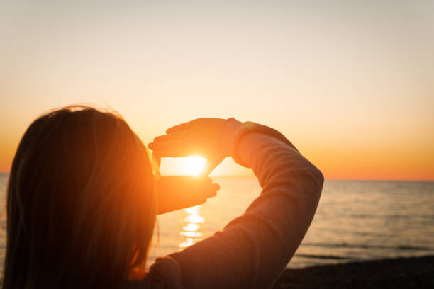 istock Hand reaching for sun. Sunset sun over the sea. 1074852054