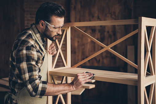 Plank panel wall unit wardrobe storage stand decorative creativity people person concept. Side profile closeup photo of serious stylish modern guy using abrasive paper for removing thorns splinters