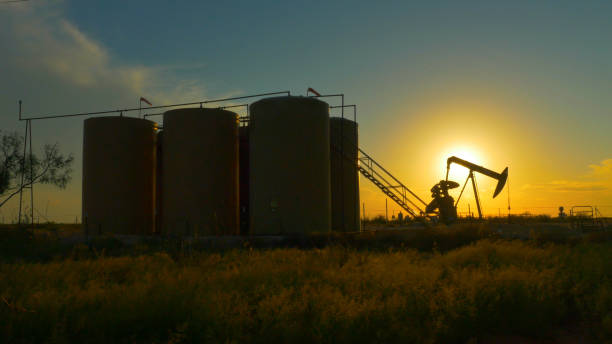 plate-forme de pompe industrielle jack pompage de pétrole brut contre soleil coucher de soleil - oil pump flash photos et images de collection