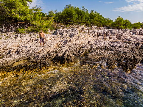 Men standing in the rocks of Mlini Beach in Croatia coastline, Dalmatian Region