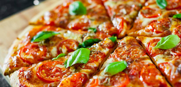 sliced Pizza with Mozzarella cheese, Tomatoes, pepper, Spices and Fresh Basil. Italian pizza. Pizza Margherita or Margarita