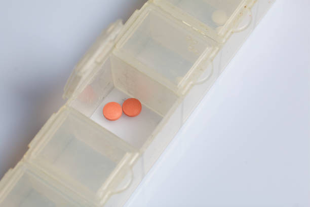 istock Two pink pills in an open pill box. On a white background. 1074859592