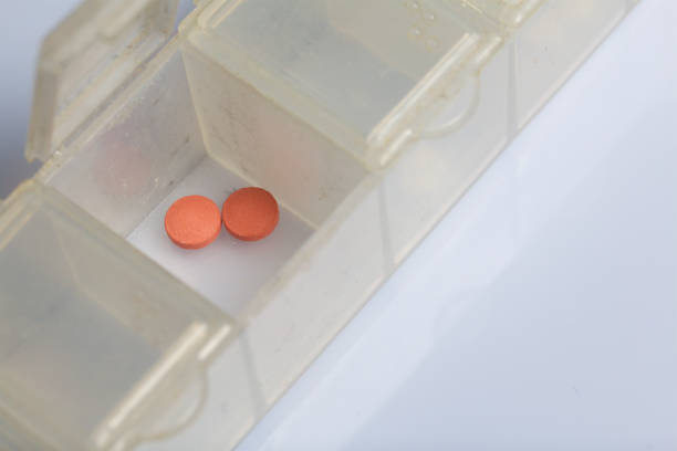 istock Two pink pills in an open pill box. On a white background. 1074859598