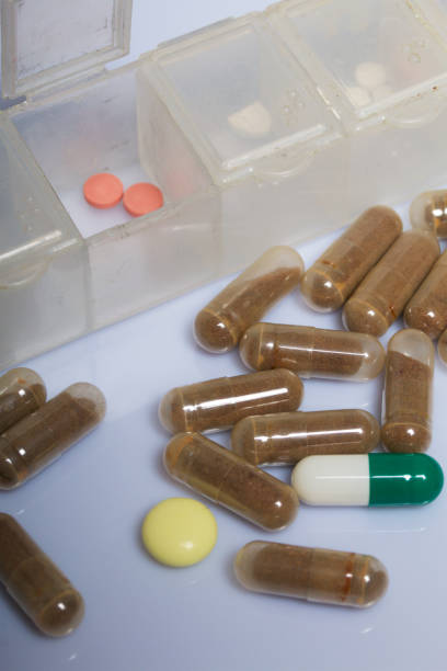 istock Two pink pills in an open pill box. Near scattered different pills. On a white background. 1074859628